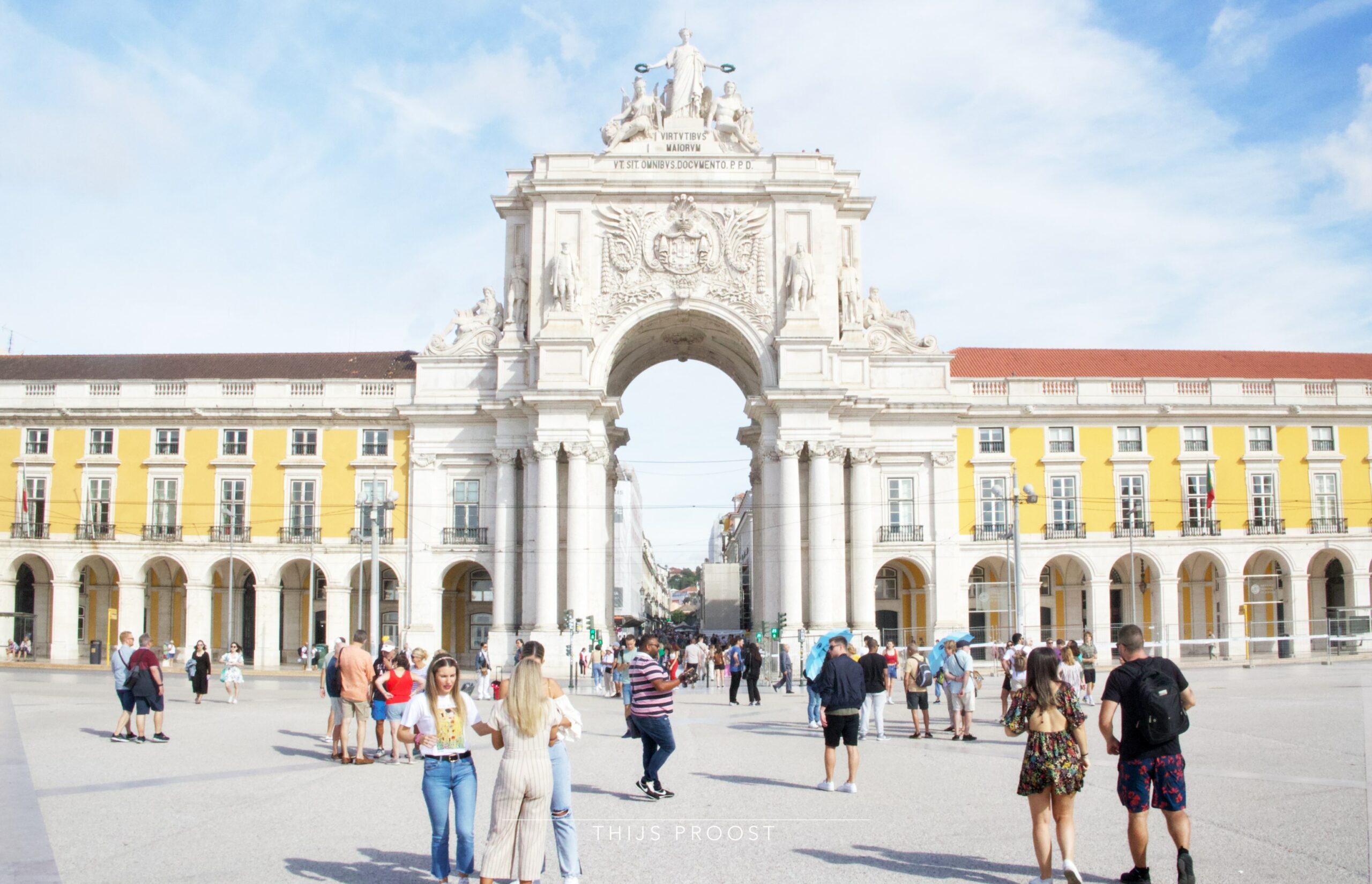 A view of the main entrance of Praça do Comércio in Lisbon Portugal on a clear day. Tourist are standing arround.