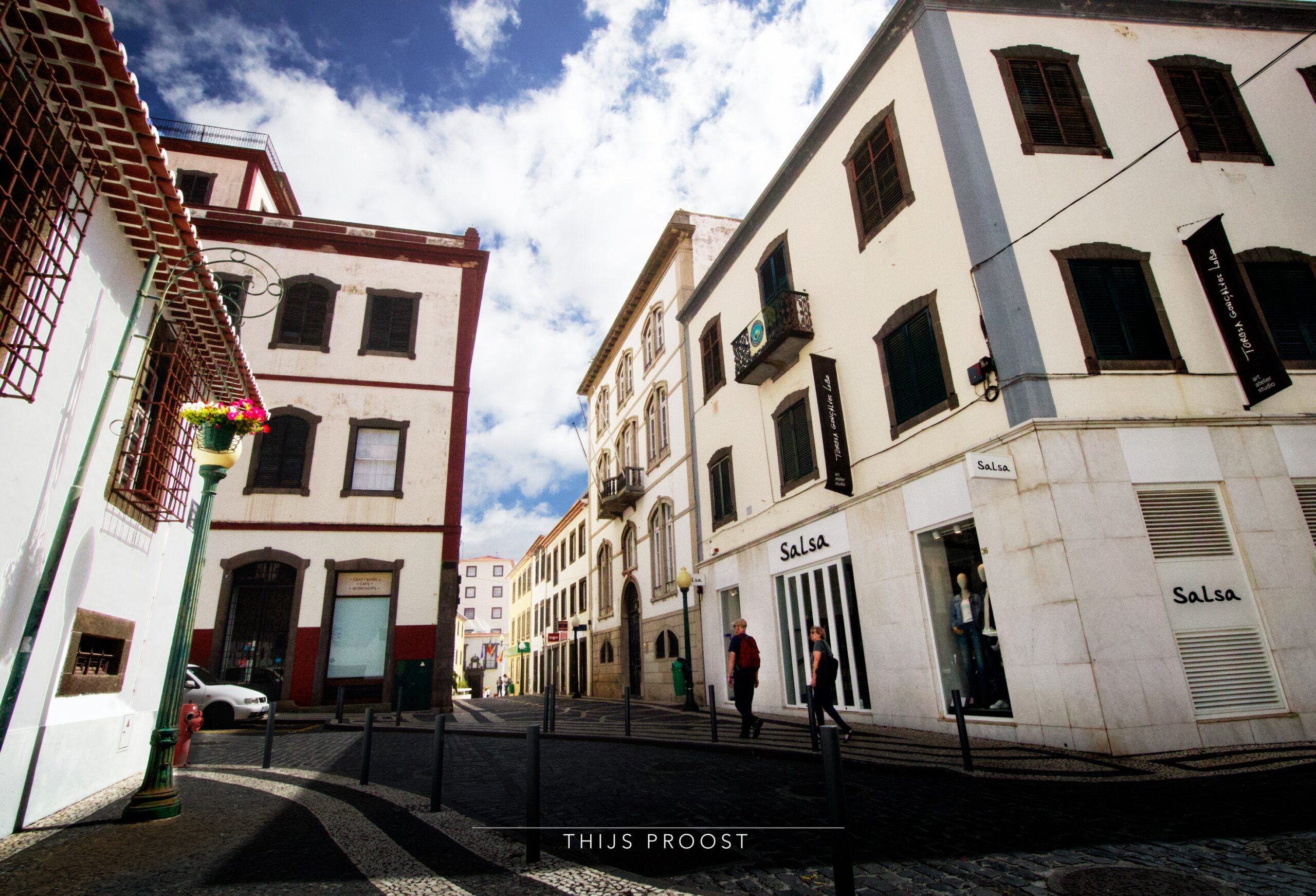 A wide angel picture of some buildings in the center of Funchal Madeira. Withe clouds with blue sky are in the center of the image.