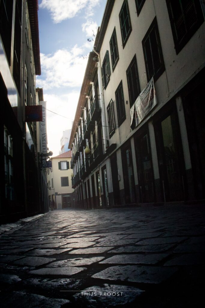 A view of a street in the center of Funchal Madiera. Taken low from the ground right above cobblestones. The sky is visible as a stripe.