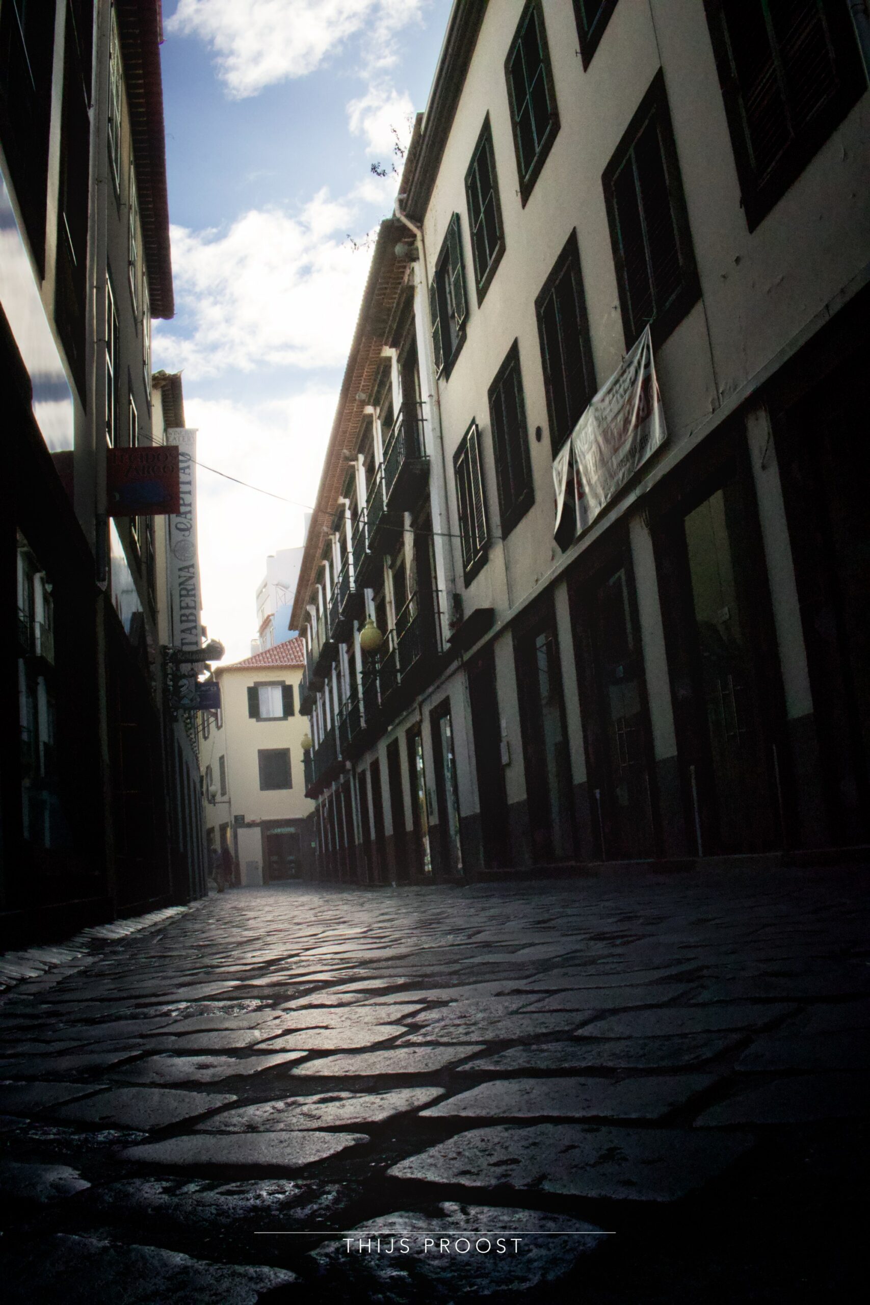 A view of a street in the center of Funchal Madiera. Taken low from the ground right above cobblestones. The sky is visible as a stripe.