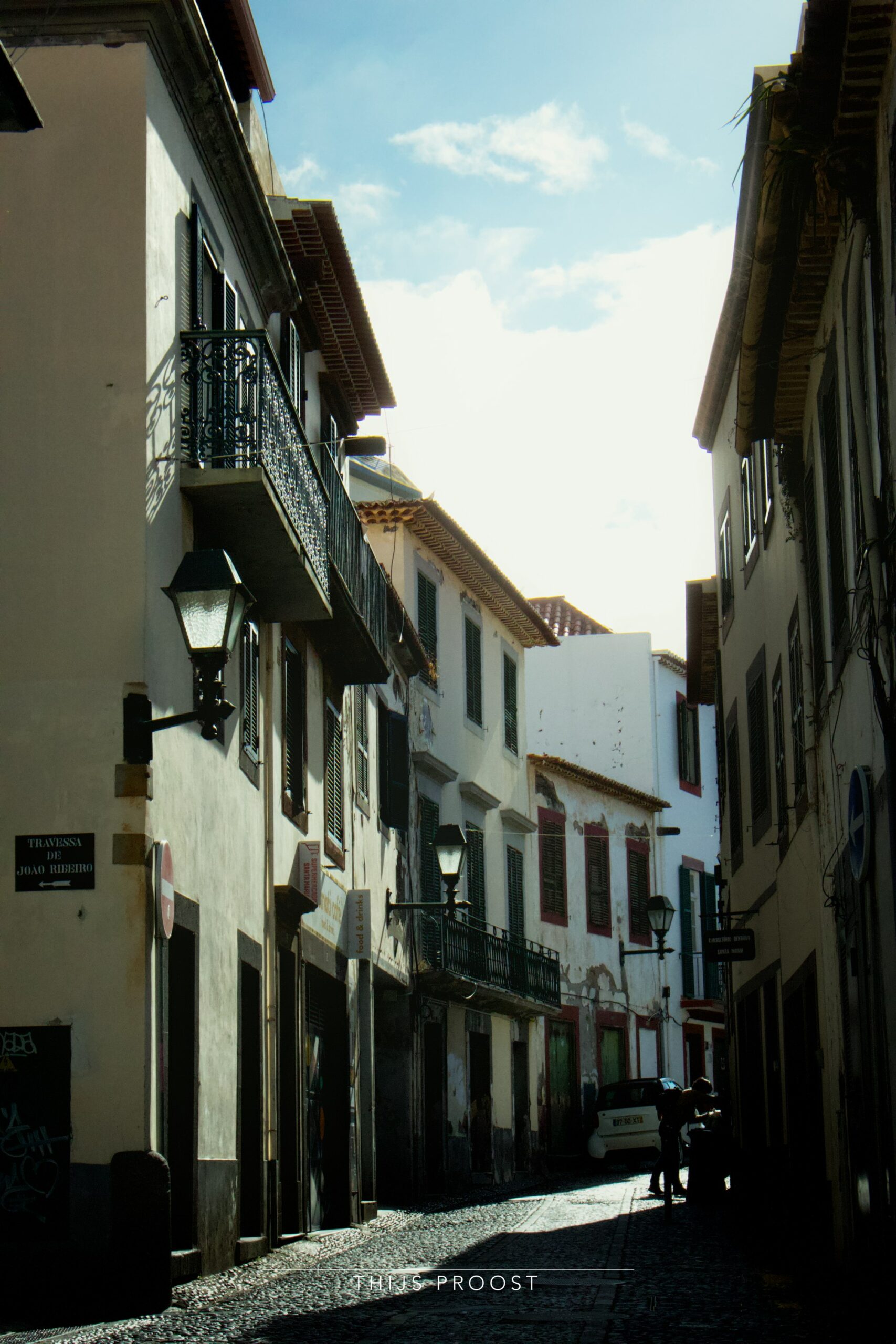 A view on a old street in the center of Funchal Madeira. Light falls on the cobblestones in the center of the street.