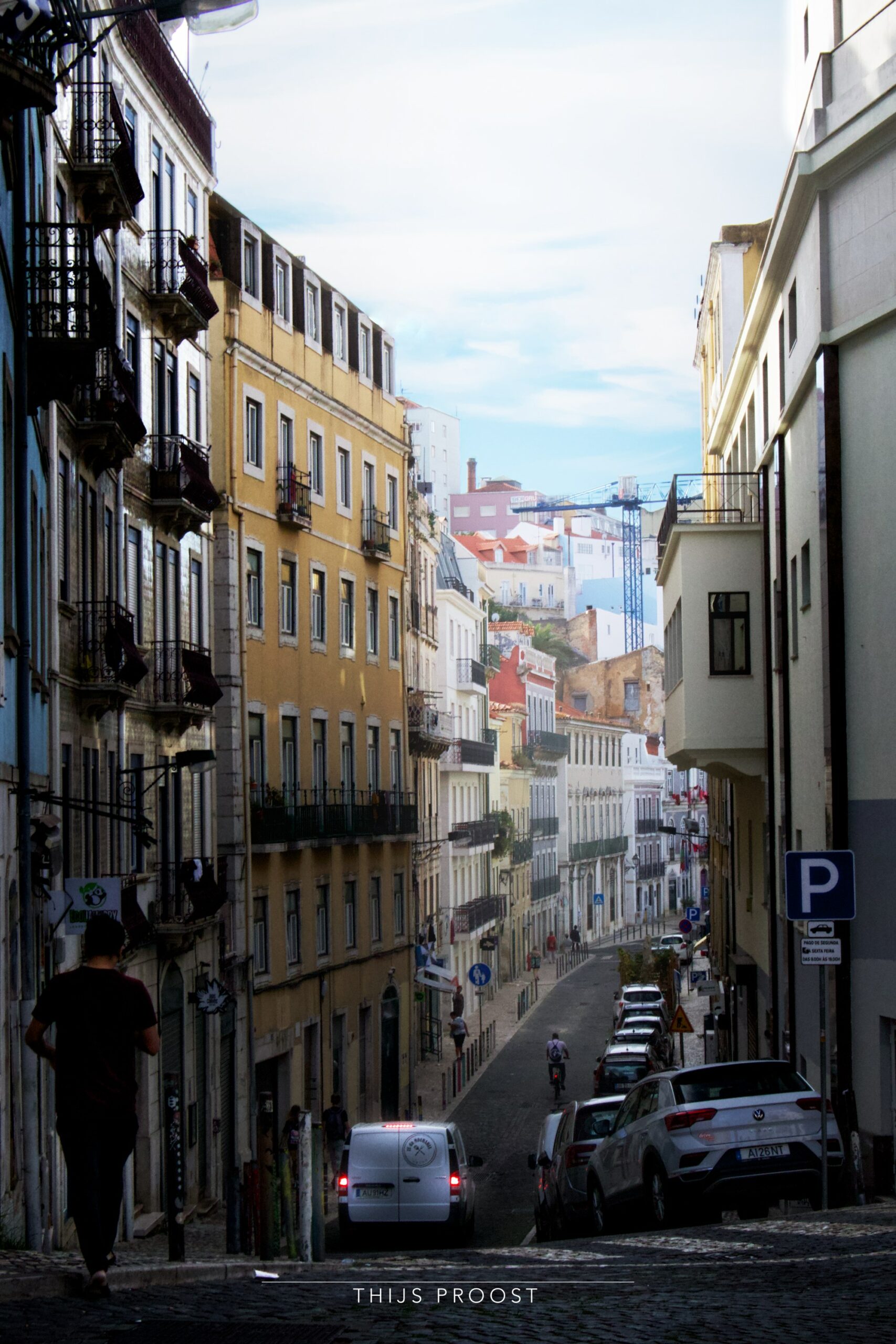 A view of a street in Lisbon wat cars parked at the side.