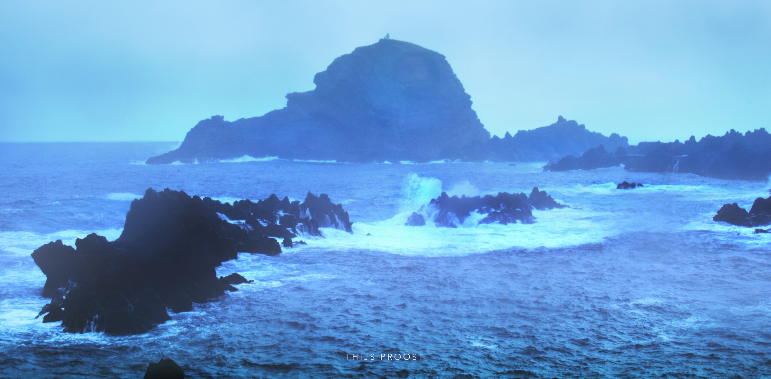 Rock in the ocean in Porto Moniz Madeira. Waves splash upward on the rocks. its a rainy day